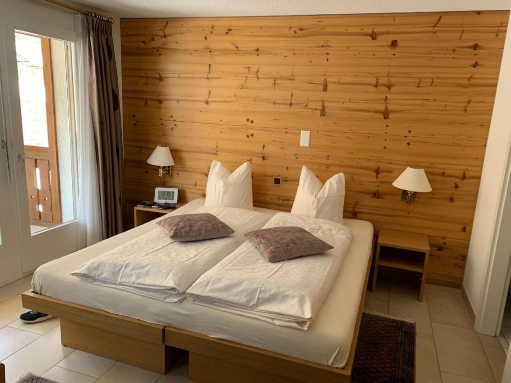 een slaapkamer met een groot bed met een houten wand bij Cozy Studio with Wellness in Goms in Blitzingen