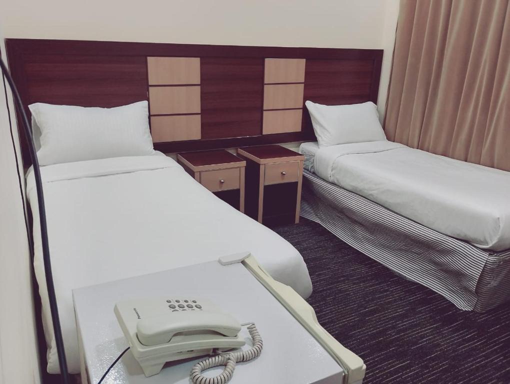 een kamer met twee bedden met een telefoon erop bij فندق الواحة الماسية 2 in Quai