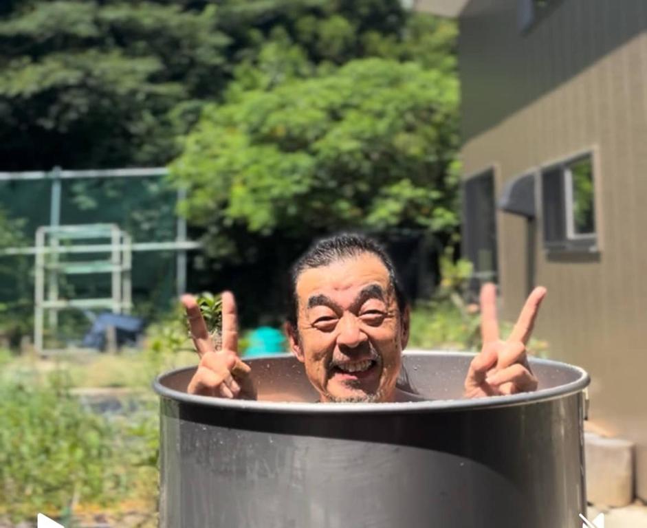 a man in a pot with his fingers up at ログハウス1棟貸し,持込み自由,サウナ,露天風呂にバーべキュウや薪割り,ソーメン流しに収穫体験が楽しめます in Kashima
