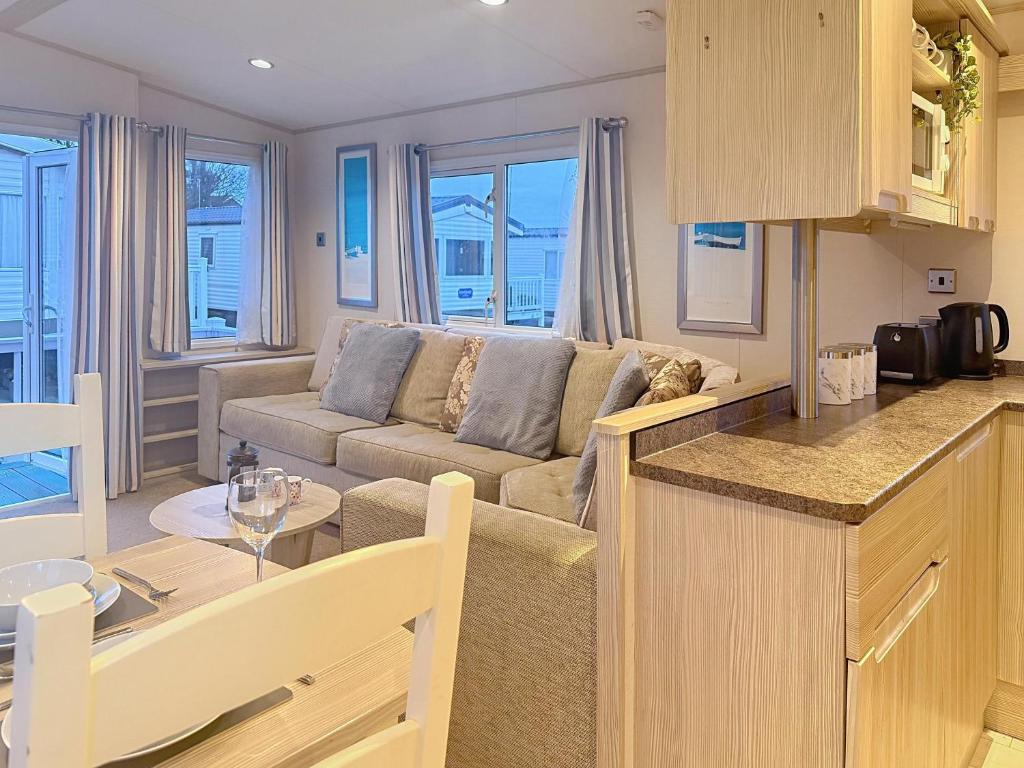 una cucina e un soggiorno con un divano e un tavolo di Dog Friendly 6 Berth Caravan With Decking Close To Pakefield Beach Ref 68067B a Pakefield