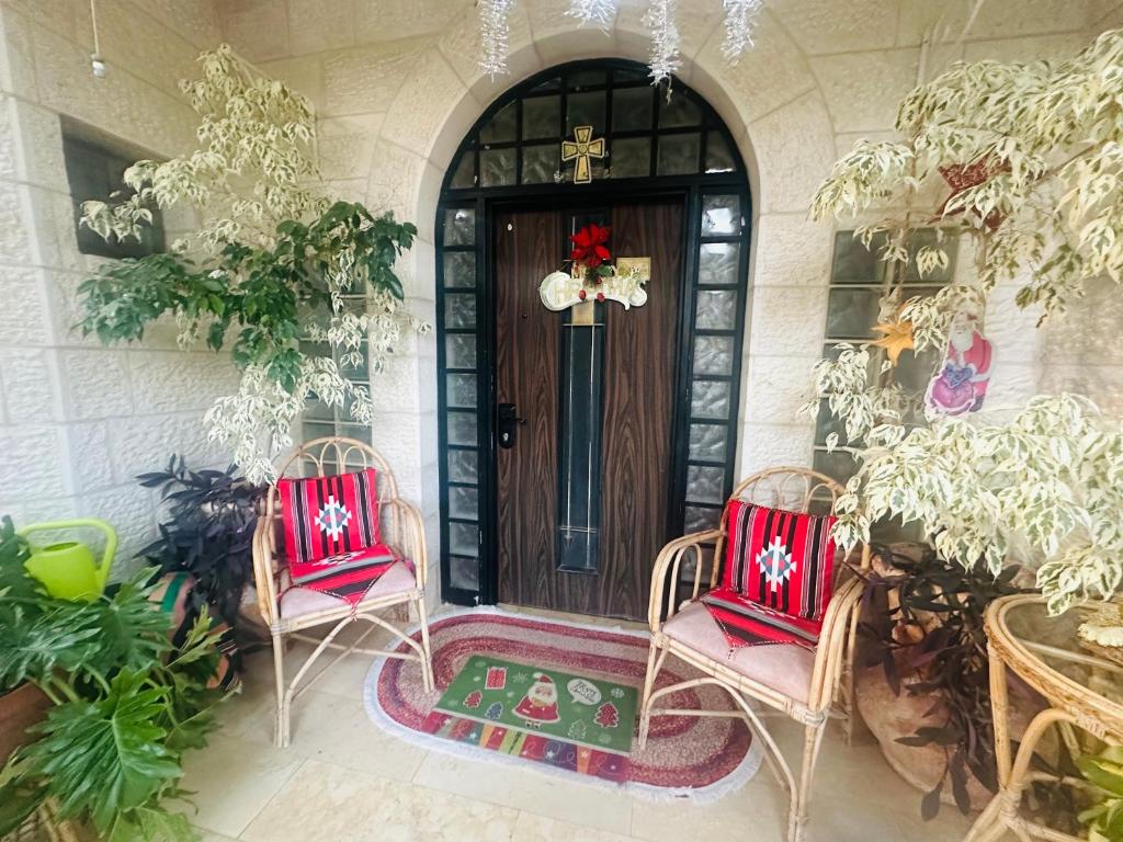 Un porche con dos sillas y una puerta con una corona. en Hayek Guest Villa, en Bethlehem