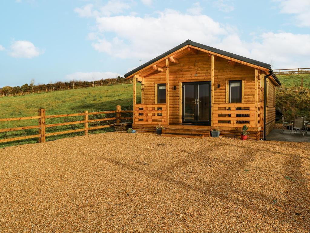 a wooden cabin in a field next to a fence at Glenview Log Cabin in Ballycastle