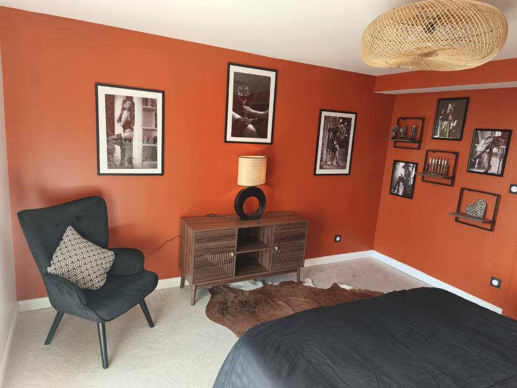 een slaapkamer met oranje muren, een stoel en een tafel bij Cocon sensuel - Jaccuzzi et petit déjeuner - Proche Chantilly et Beauvais in Clermont