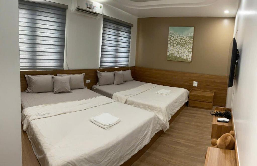 two twin beds in a room with two windows at Shining Hotel Son La in Bản Bố Pua