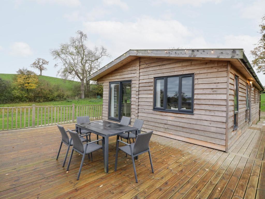 a tiny house with a table and chairs on a deck at Cedar Lodge in Rugeley