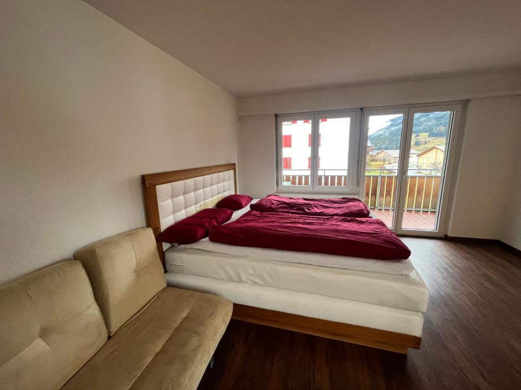 ein Schlafzimmer mit einem Bett und einer Couch und einem Fenster in der Unterkunft Satin Home in Savognin