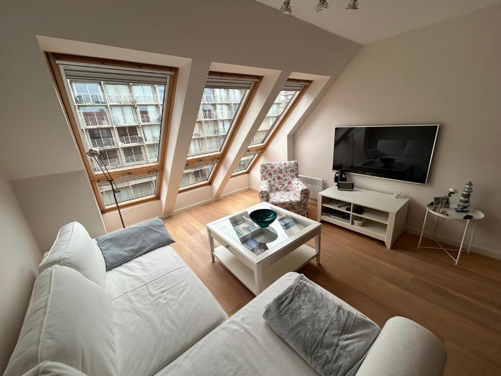a living room with a white couch and a tv at Residence Rodin in Nieuwpoort