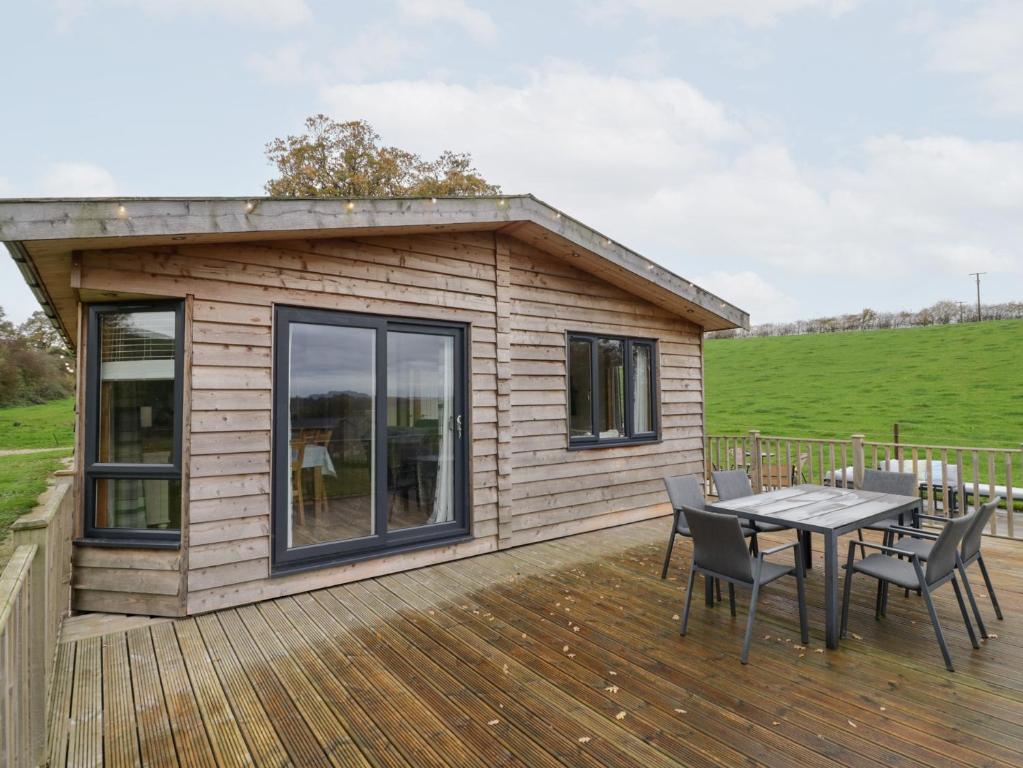 a small cabin with a table and chairs on a deck at Elm Lodge in Rugeley