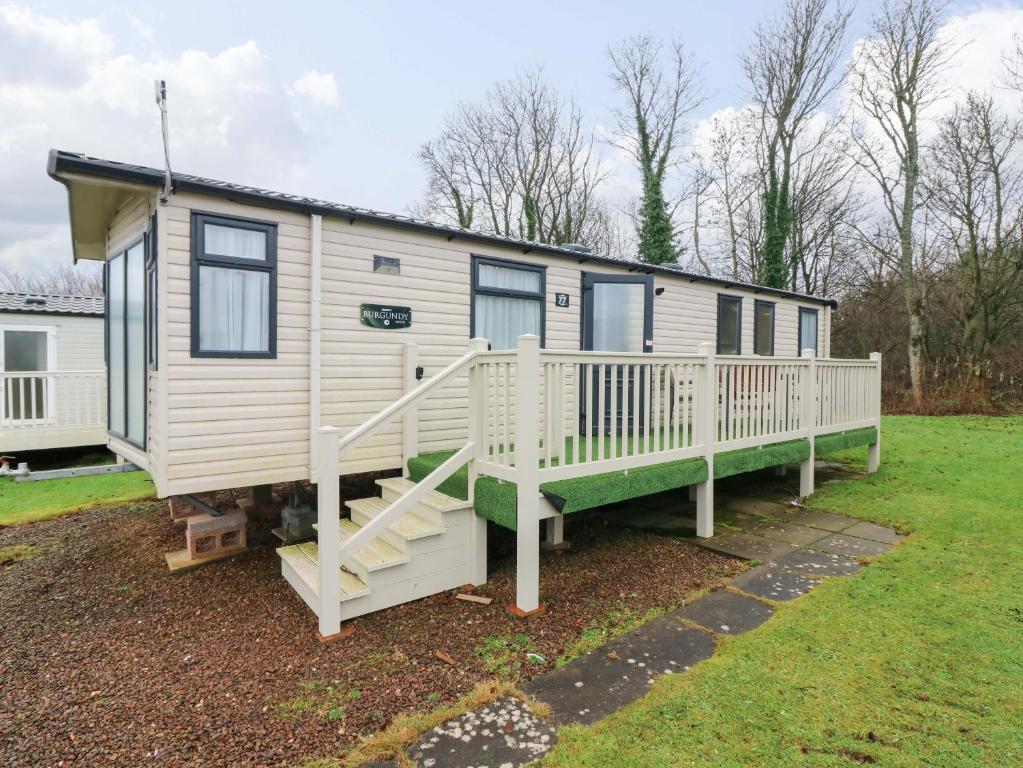 a tiny house with a porch and a staircase at Caravan number 77 in Eyemouth