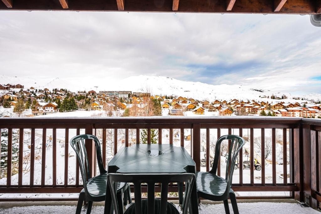 un tavolo e sedie su un balcone con una montagna innevata di Duplex confortable avec piscine a La Toussuire