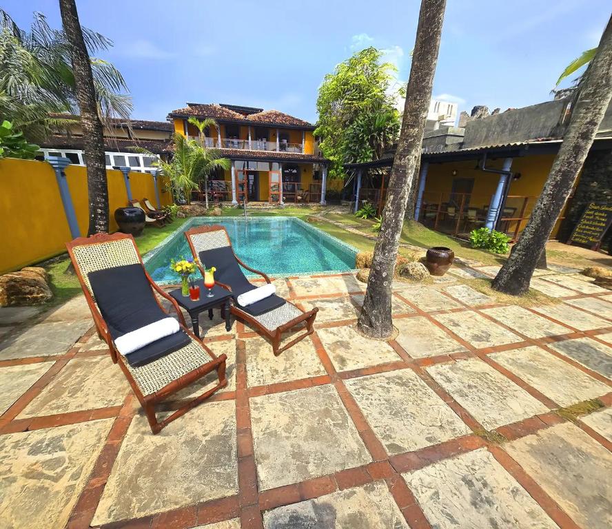 twee stoelen en een tafel naast een zwembad bij Villa Kusum in Hikkaduwa