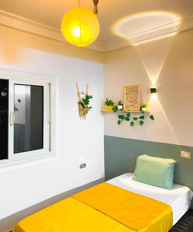 a bedroom with a bed with a yellow blanket on it at Jme Bunks Hostel in Aswān
