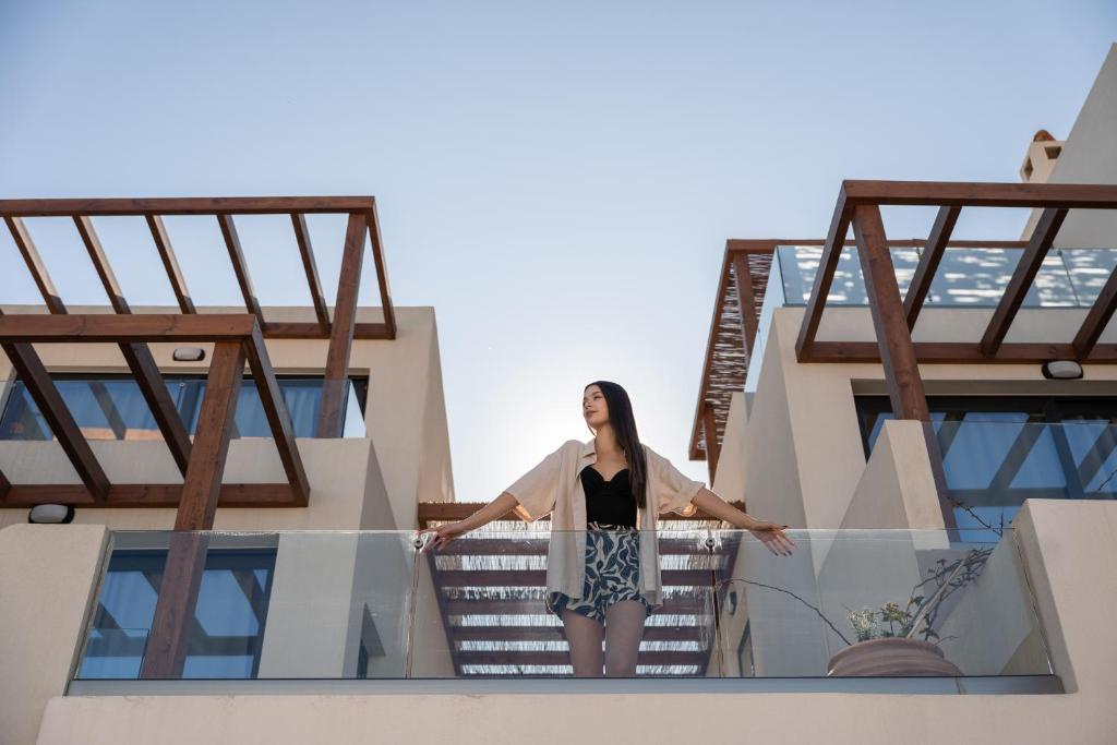 a woman standing on the balcony of a building at VAYA Suites by Omilos Hotels in Amoudara Herakliou