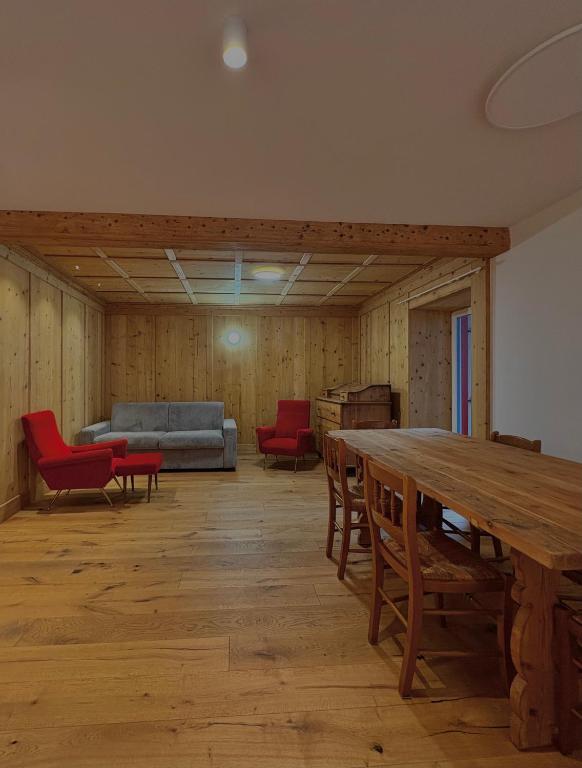 een grote kamer met een tafel en stoelen en een bank bij Casa Patty Moena in Moena