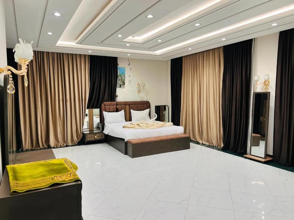 una camera con letto in una stanza con tende di تحت التجهيز a ‘Aţţān