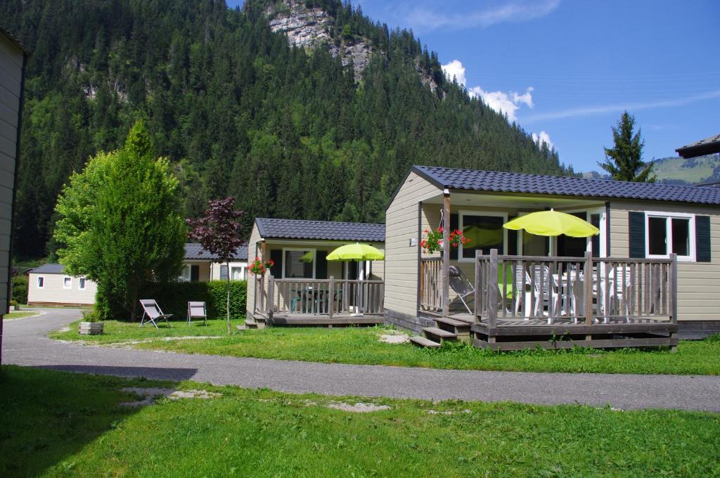 a house with a deck with umbrellas on it at Camping L'Oustalet in Châtel