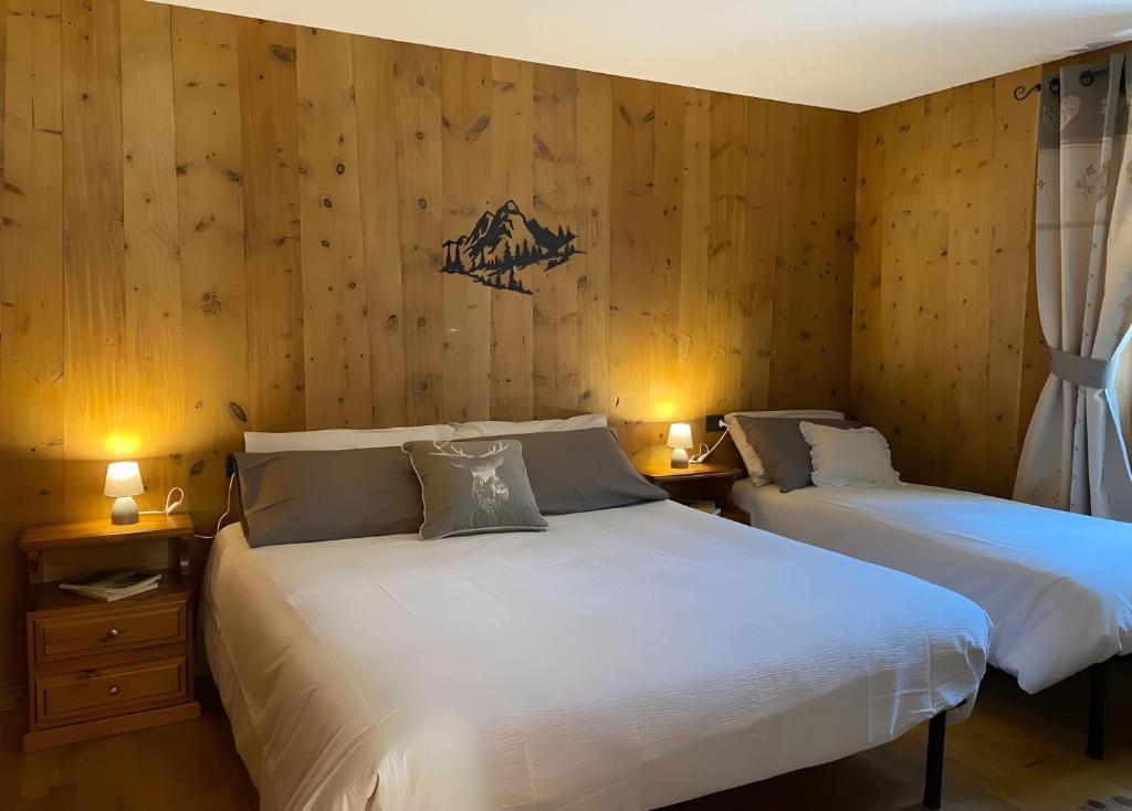 due letti in una stanza con pareti in legno di Appartamento Le Cigamole a Valfurva