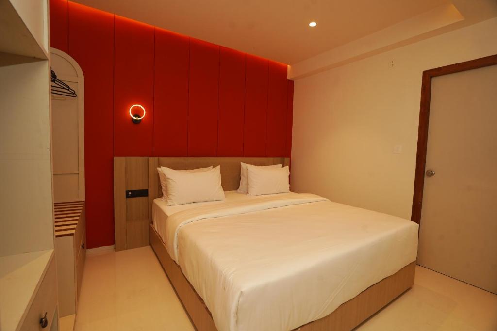 een slaapkamer met een bed met een rode muur bij Hotel Harriet in Rāmeswaram