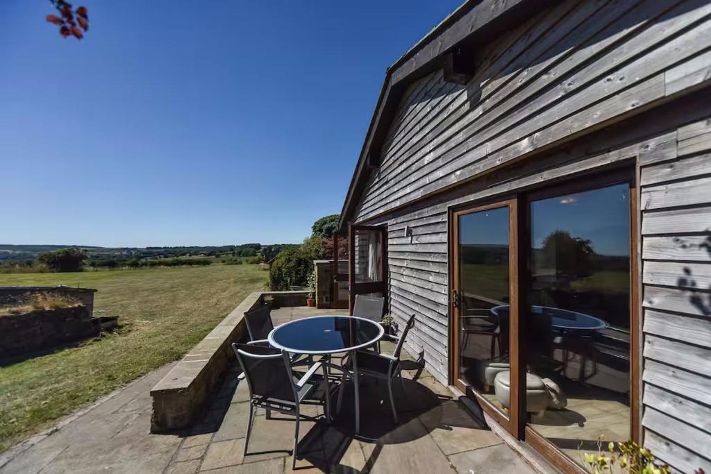 a patio with a table and chairs next to a building at Amber Cabin in Ashover