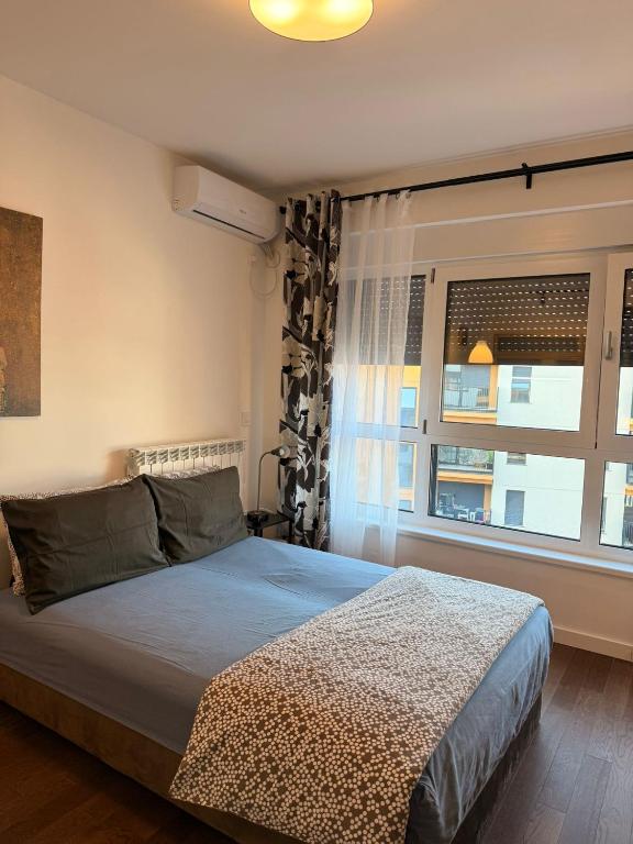 a bedroom with a large bed and a window at Fantasia apartmani - Tesla palace in Kragujevac