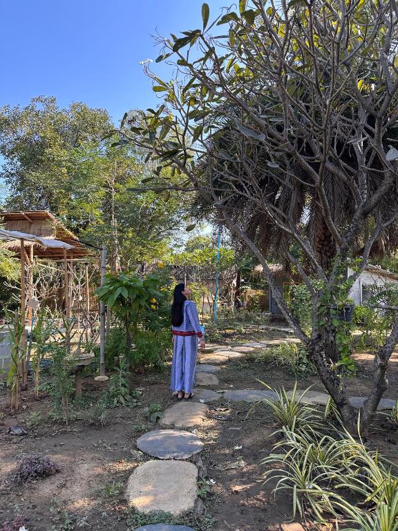 a woman walking down a path in a garden at Faiza Farm home in Ban Nong Phai