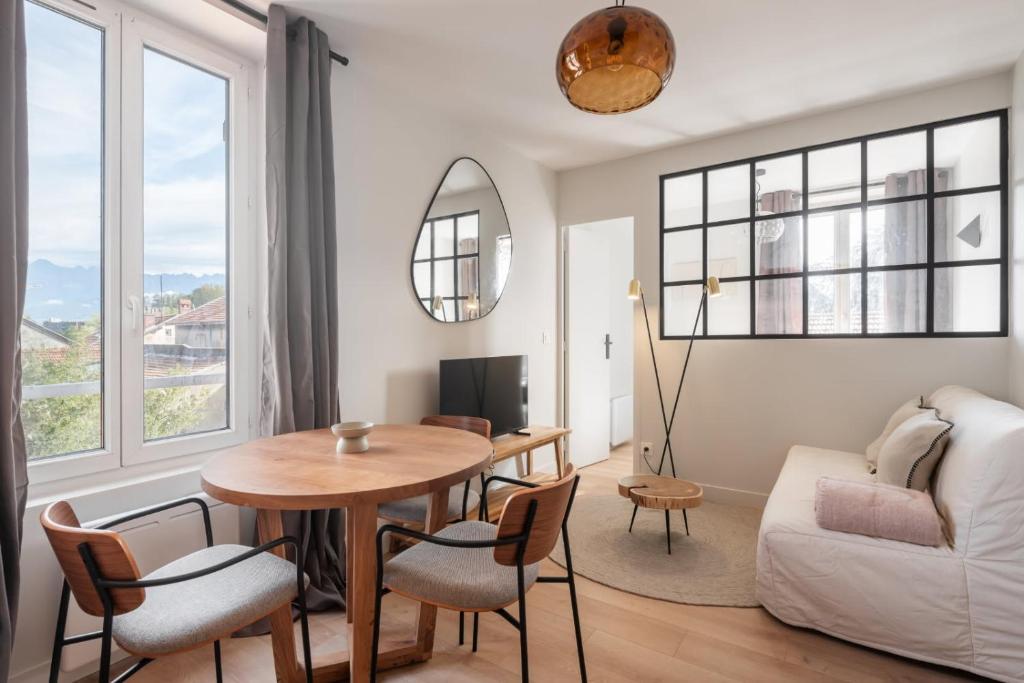 een woonkamer met een tafel, stoelen en een bank bij Marrakech - Gare - CEA - STMicro in Fontaine