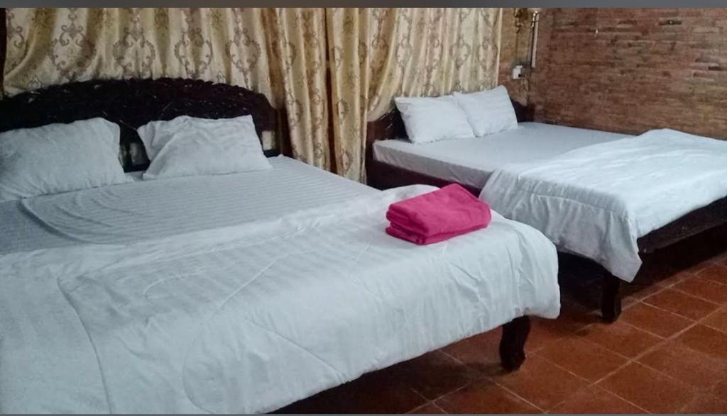 two beds with a pink bag on top of them at Kampot Riverside GuessHouse in Phumĭ Ândong Pring