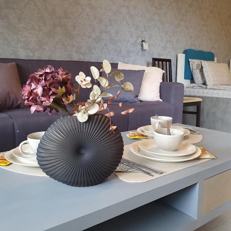 einen Tisch mit Platten und eine Vase mit Blumen darauf in der Unterkunft Lake View Deluxe Tryavna in Trjawna