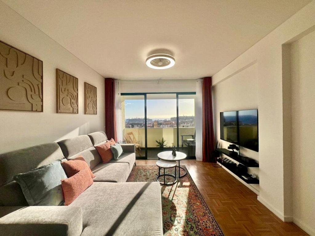 een woonkamer met een bank en een groot raam bij View in Bicas