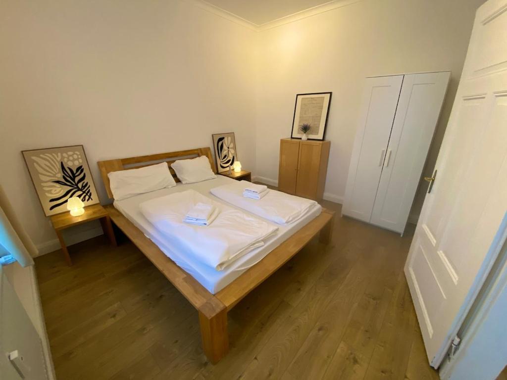 Schlafzimmer mit einem Bett mit weißer Bettwäsche und Holzböden in der Unterkunft Studio Apartment nahe Lüneburg in Bienenbüttel