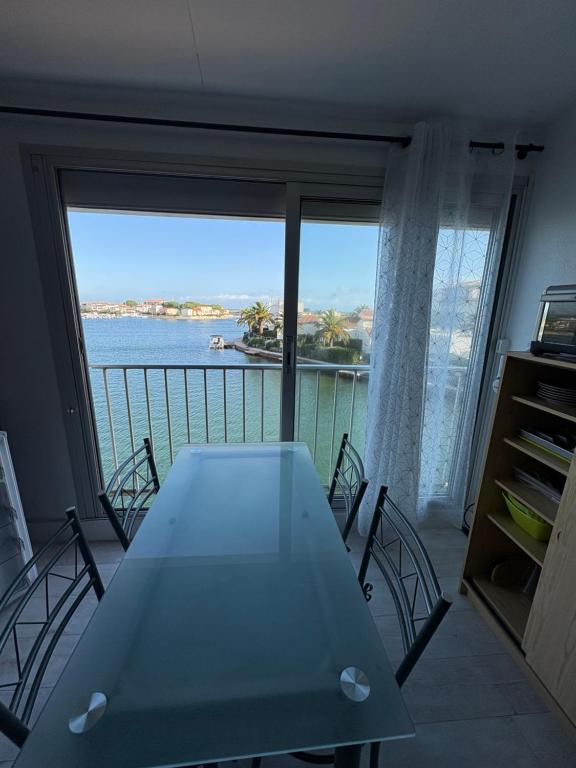 Zimmer mit einem Tisch und Blick auf das Wasser in der Unterkunft Marinelle in Saint Cyprien Plage