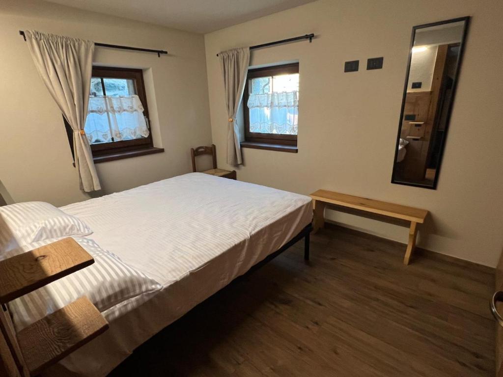 een slaapkamer met een bed en een tafel en twee ramen bij La Boschera in Champoluc