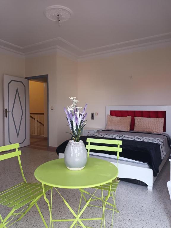 a bedroom with a bed and a green table and chairs at Villa Hay Riad - Harhoura in Temara