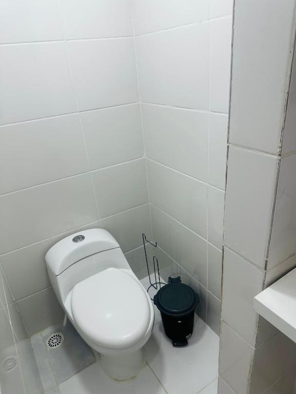 a bathroom with a white toilet and a black bucket at Pousada Montblanc suíte 4 in Guarujá