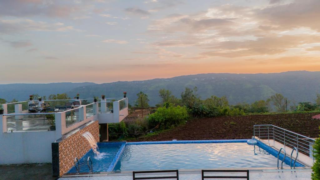 a swimming pool on top of a house with a mountain at Strawberry King Resort in Mahabaleshwar