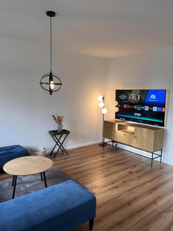 ein Wohnzimmer mit einem blauen Sofa und einem Flachbild-TV in der Unterkunft Ruhig & großzügig für 8 Pers, WLAN & Feuerschale in Rahden