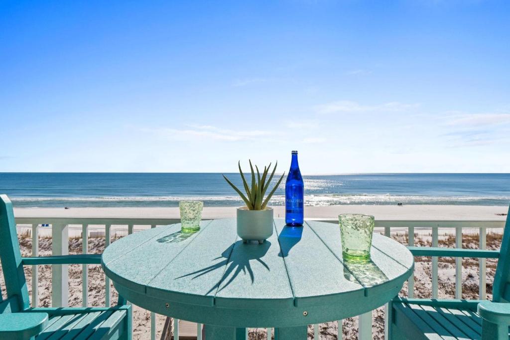 stół z niebieską butelką i szklankami na plaży w obiekcie Gulf Dunes 416 w mieście Fort Walton Beach