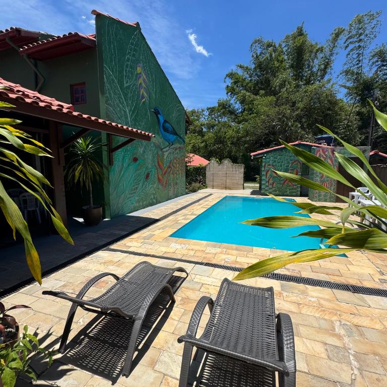 a patio with two chairs and a swimming pool at Chales da Lua Juquehy in Juquei