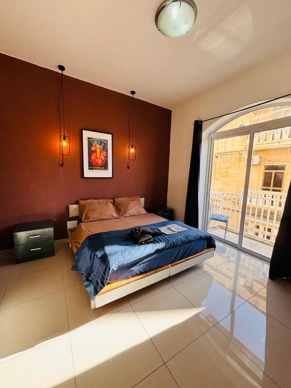 een slaapkamer met een bed en een groot raam bij Sliema Central with Balcony Airconditioned and Comfortable Self Check IN in Il-Gżira