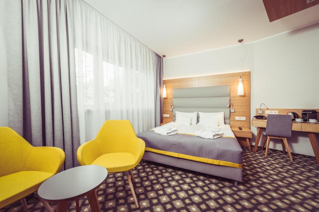 a hotel room with a bed and chairs and a desk at Hotel Vivaldi in Poznań