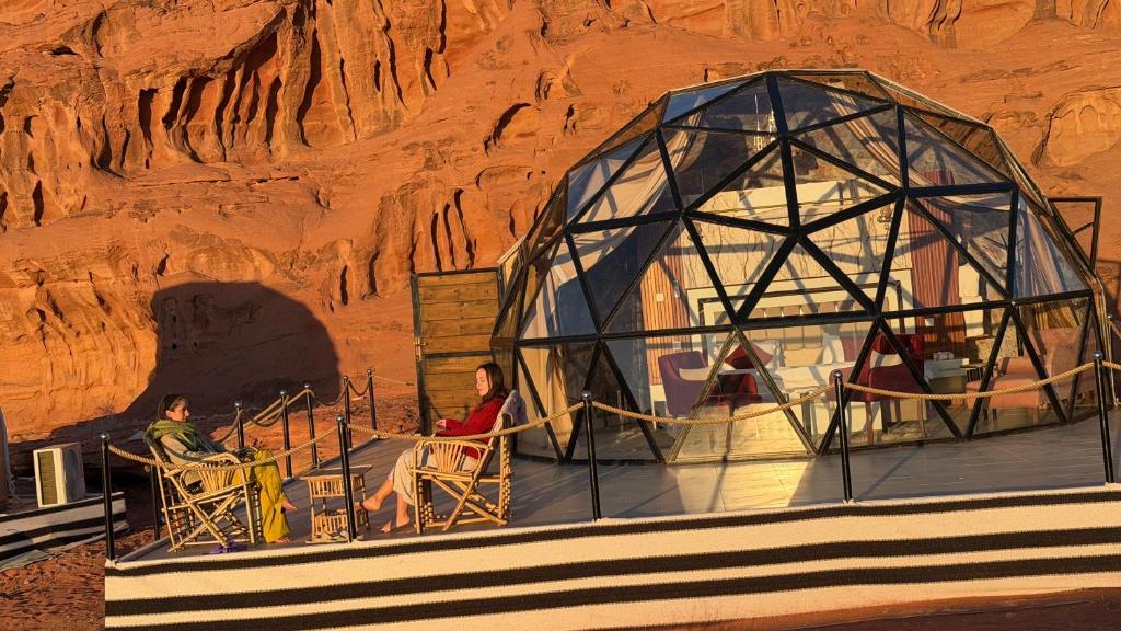 due persone sedute su delle sedie all'esterno di una casa a cupola di Desert Bedouin adventure a Wadi Rum