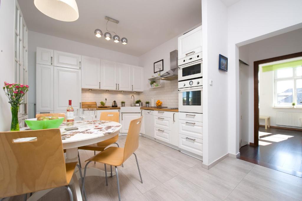a kitchen with white cabinets and a table and chairs at Sunny Sopot in Sopot