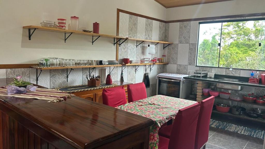 une cuisine avec une table en bois et des chaises rouges dans l'établissement Casa da Barra, à Ubatuba