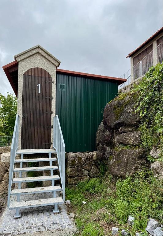 a green building with a staircase leading to a door at Canastro do Carvalho in Anissó