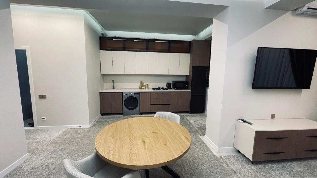 a living room with a wooden table and a kitchen at Kamoli Khujandi 166 in Khujand