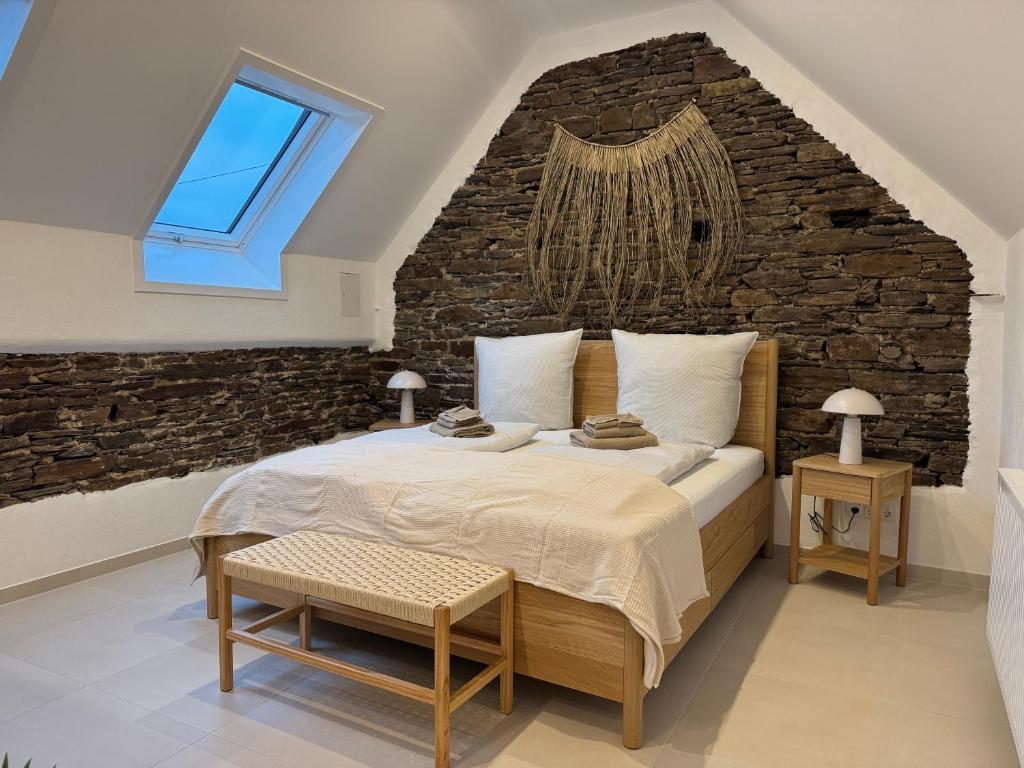 een slaapkamer met een groot bed met een bakstenen muur bij Zur Fausenburg in Bruttig-Fankel