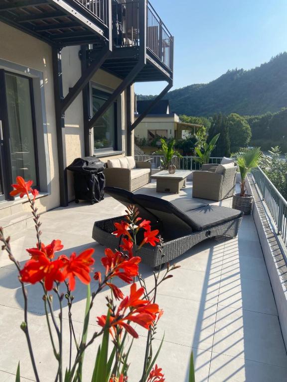 a patio with red flowers in front of a house at Zur Fausenburg in Bruttig-Fankel