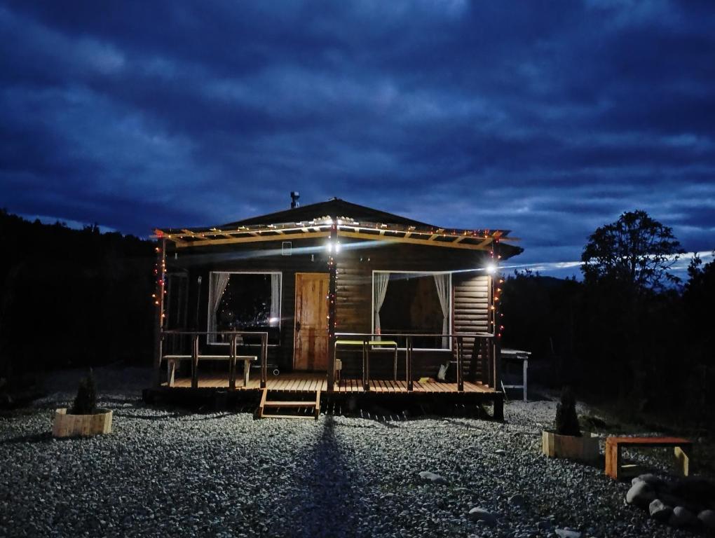 een kleine hut met een verlichte veranda 's nachts bij Cabaña colonia río sur in Puerto Varas