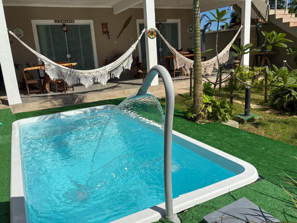 a pool with a water fountain in front of a house at Chalé do Gaúcho in Ubatuba