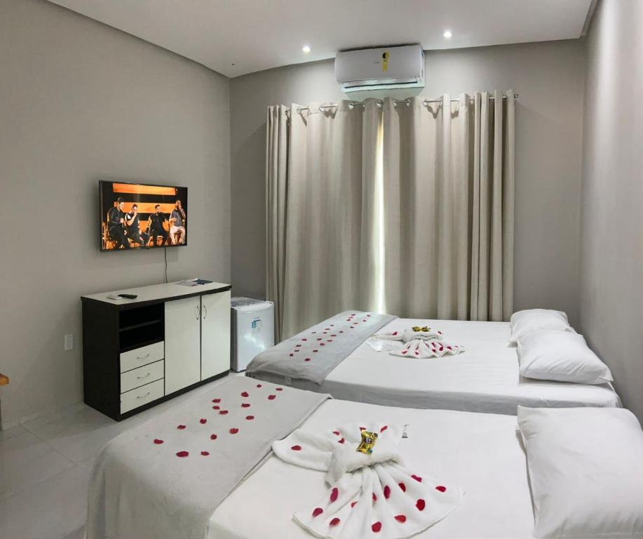 twee bedden in een kamer met rode rozen erop bij Serra Village Hotel in Ubajara